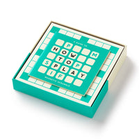 A turquoise box from Brass Monkey features the Scrumble Magnetic Fridge Game—its cover shows letter tiles spelling out the game’s name in a crossword-style, with the magnetic board partially lifted from the box.