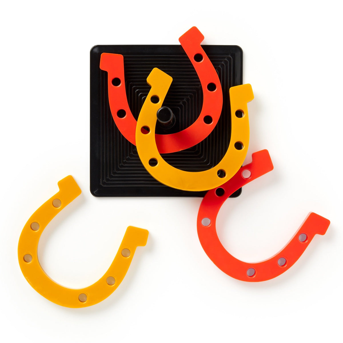 Three plastic horseshoes—two yellow, one orange—lean against a black square target with a vertical peg. The Brass Monkey Giddy Up Tabletop Horseshoes Game features holes along each horseshoes sides and is set on a white background.