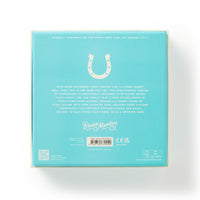 The back of the turquoise Giddy Up Tabletop Horseshoes Game box displays a horseshoe graphic at the top, fun gameplay details, and Brass Monkey branding with company info and icons at the bottom.