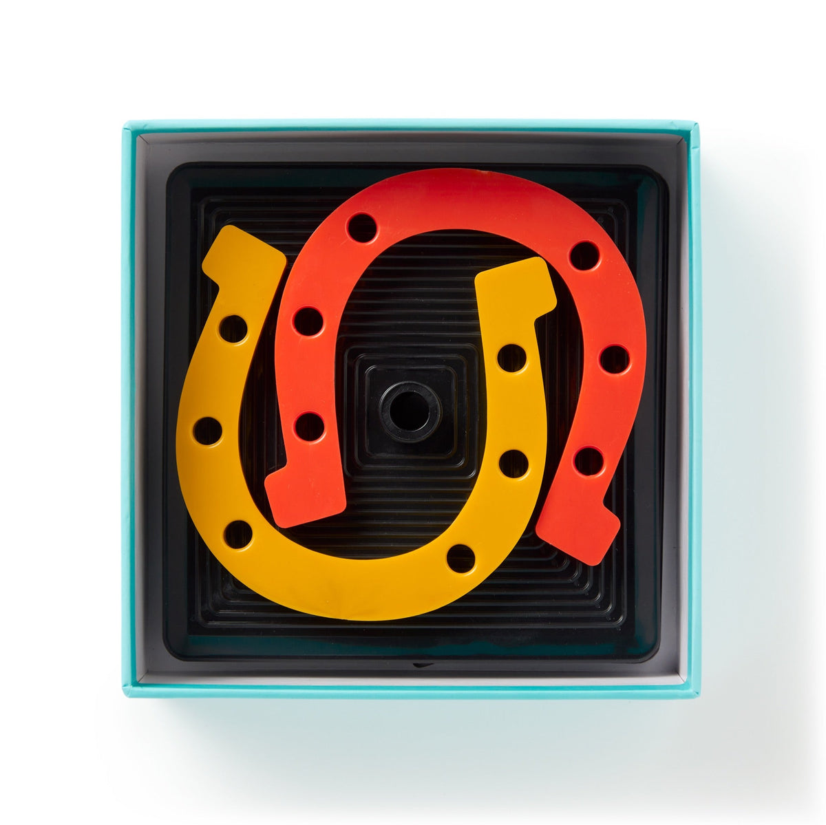The Brass Monkey Giddy Up Tabletop Horseshoes Game includes a square box with yellow and red rubber horseshoes on a black tray featuring a raised center peg—perfect for indoor parties.