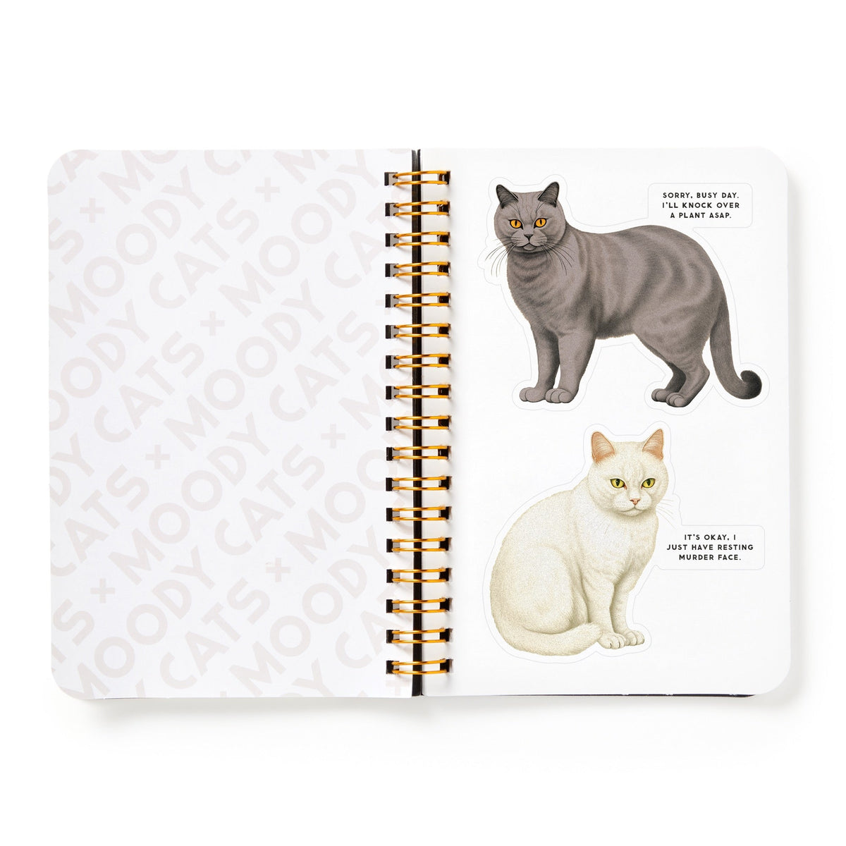 An open spiral notebook features two Moody Cats from the Brass Monkey Sticker Book: a gray cat saying, Sorry, busy day, I’ll knock over a plant ASAP, and a white cat replying, It’s okay. I just did something mischievous.