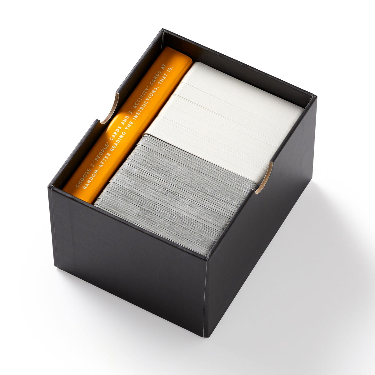 The Of All The People Social Game by Brass Monkey comes in a black box with three neatly organized sections of orange, white, and gray cards for a fun card game experience.