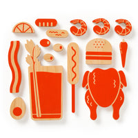 The (Over) Loaded Bloody Mary Balance Game by Brass Monkey includes orange and beige wooden pieces like shrimp, bacon, burger, chicken, corn dog, egg, carrot, lemon slice garnishes, celery stalk, bread, and a drink for perfect play.