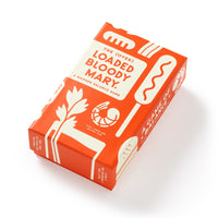 A rectangular orange box labeled “(Over) Loaded Bloody Mary Balance Game” by Brass Monkey features white illustrations of classic Bloody Mary garnishes like celery and olives on its packaging.