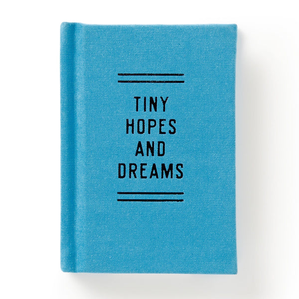 The Brass Monkey Tiny Hopes and Dreams Tiny Diary is a small blue pocket journal with “TINY HOPES AND DREAMS” printed in black, centered on the cover between black lines. The product is shown against a white background.