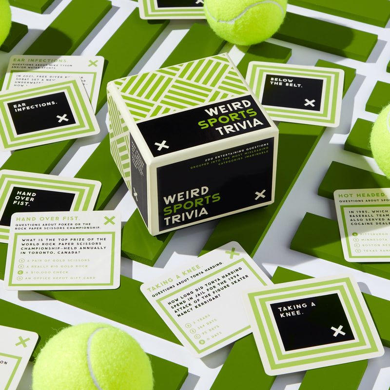 A box of Brass Monkeys Weird Sports Trivia rests on a green and white surface, surrounded by trivia cards and tennis balls. The cards feature obscure sports facts on a geometric green-patterned background—ideal for sports enthusiasts.