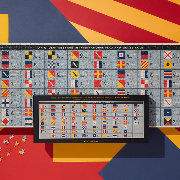 The Brass Monkey An Urgent Message 1,000 Piece Panoramic Puzzle features the international flag alphabet and Morse code, plus a guide below linking each letter to its flag and Morse code for easy identification.