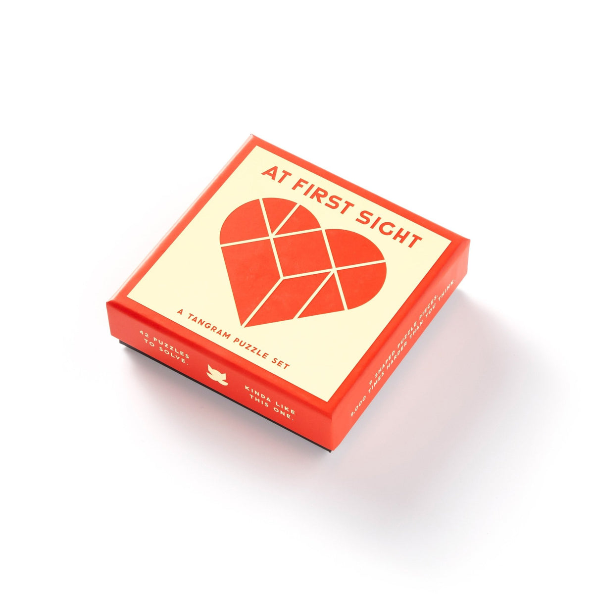 A red and cream box labeled At First Sight features an abstract heart design; inside is a unique tangram puzzle set from Brass Monkey.