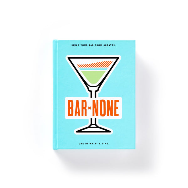 A vibrant blue Bar None Drink Journal by Brass Monkey features a martini glass and bold orange title. The cover invites you to build your bar from scratch with cocktail recipes and inspiration.