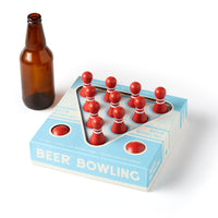 The Brass Monkey Beer Bowling Drinking Game Set features red MDF pins, a bottle, and is displayed on a blue and white box with bowling lane graphics and circular cutouts.