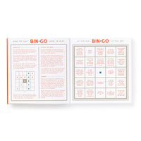 The Brass Monkey Bin-go Get Some Drinks Bingo Book features an open spread showing game instructions on the left and a bingo card with people-watching prompts on the right, including one square marked with an X.