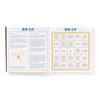 The Brass Monkey Bin-go To A Dumb Meeting Bingo Book features instructions for playing on the left page and a Bingo grid on the right filled with phrases like “Let’s circle back” and “You’re on mute.”.