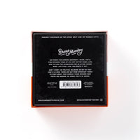 The image shows the back of a square black box with Brass Monkey at the top and details about the Debatable Game Set—a social game with debate cards on hot button topics—plus website, social media handle, and barcode underneath.