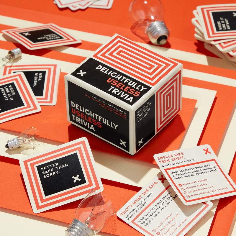 Brass Monkey’s Delightfully Useless Trivia features quirky questions, phrases, and sneaky categories to stump your friends—a fun trivia set packaged in a bright orange and white box.