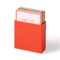 The Emergency Affirmations for Exceptionally Stupid Days Card Deck by Brass Monkey comes in a red box with colorful cards inside—the top one partially reveals the bold message DONT BE, perfect for instant pick-me-ups.