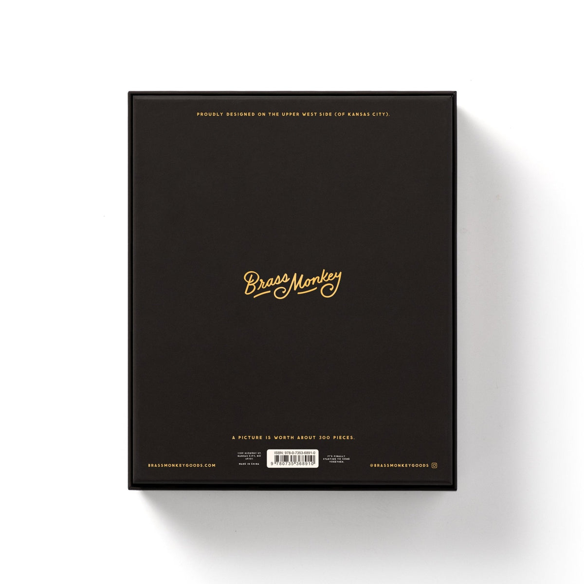 The back of a black rectangular box features gold text reading Brass Monkey in the center, with smaller gold and white details—ideal for fans of the Employee Of The Month 300 Piece Apartment Puzzle by Brass Monkey—set against a white background.
