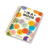 The Brass Monkey In A Mood Sticker Book is spiral-bound and features a white cover with colorful circles displaying moody emoticons that represent a variety of emotions.