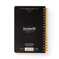A black spiral-bound sticker book by Brass Monkey, titled In A Mood in white text. “Stick it to em” is below, with moody emoticons and a barcode featuring product details at the bottom.