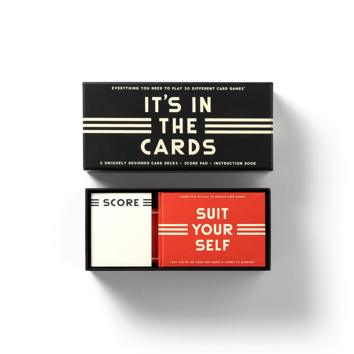 The Brass Monkey Its In The Cards Playing Card Game Set features two decks—Score and Suit Yourself—and an instruction book, all organized in a sleek black box with the lid off, perfect for card enthusiasts.