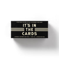 The Brass Monkey Its In The Cards Playing Card Game Set is a black rectangular box with cream text, including 2 card decks, a score pad, an instruction book, and rules for 30 card games.
