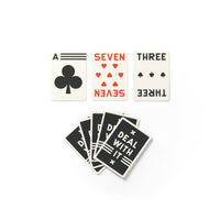 Three cards from the Brass Monkey Its In The Cards Playing Card Game Set are shown above a fan of five cards with Deal with it in bold white letters on a black background.