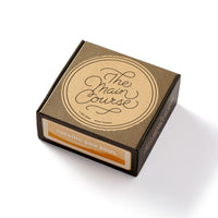 A brown cardboard box labeled “The Main Course” by Brass Monkey sits on a white surface, revealing a durable ceramic Main Course Pet Food Bowl inside, detailed with reflective gold lettering and vintage-inspired minimal packaging.