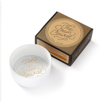 The Brass Monkey Main Course Pet Food Bowl is a white ceramic bowl with reflective gold The main course lettering, shown next to its brown square packaging featuring the same elegant script.