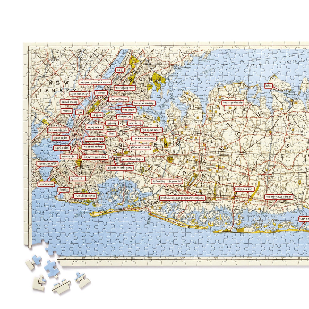 The NYC Map 1,000 Piece Panoramic Puzzle by Brass Monkey shows a vintage map of New York City with place names in red rectangles and loose pieces in the lower left corner.