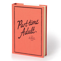 A coral hardcover Part-Time Adult Undated Daily Planner by Brass Monkey stands upright, featuring black handwritten-style text and a simple black border on the cover.