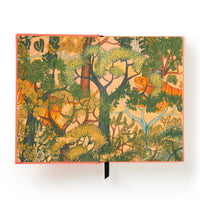 The Brass Monkey Part-Time Adult Undated Daily Planner is open, showing a vibrant forest illustration with detailed leafy trees, twisted branches, and rich foliage in green, yellow, and orange hues against a warm backdrop.