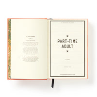 An open Part-Time Adult Undated Daily Planner by Brass Monkey displays a left-page disclaimer in small print, a large “PART-TIME ADULT” title on the right, a website at the bottom, and features a black ribbon bookmark.