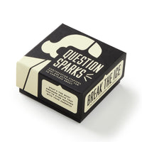 A black and cream Question Sparks box by Brass Monkey, filled with conversation starter cards, sits against a white background. BREAK THE ICE appears on the side and a sample question is printed on the edge.