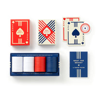 Brass Monkey’s Raise The Stakes Poker Game Set includes a deck of red and blue cards, white, red, and blue poker chips, a poker guide booklet, and an ace of spades card—all displayed on a white background.