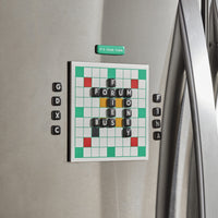 The Brass Monkey Scrumble Magnetic Fridge Game is played on a stainless steel fridge, displaying the words FORUM, FINE, BUSY, and MONEY. Letter tiles and a green “ITS YOUR TURN” magnet accent the magnetic board.