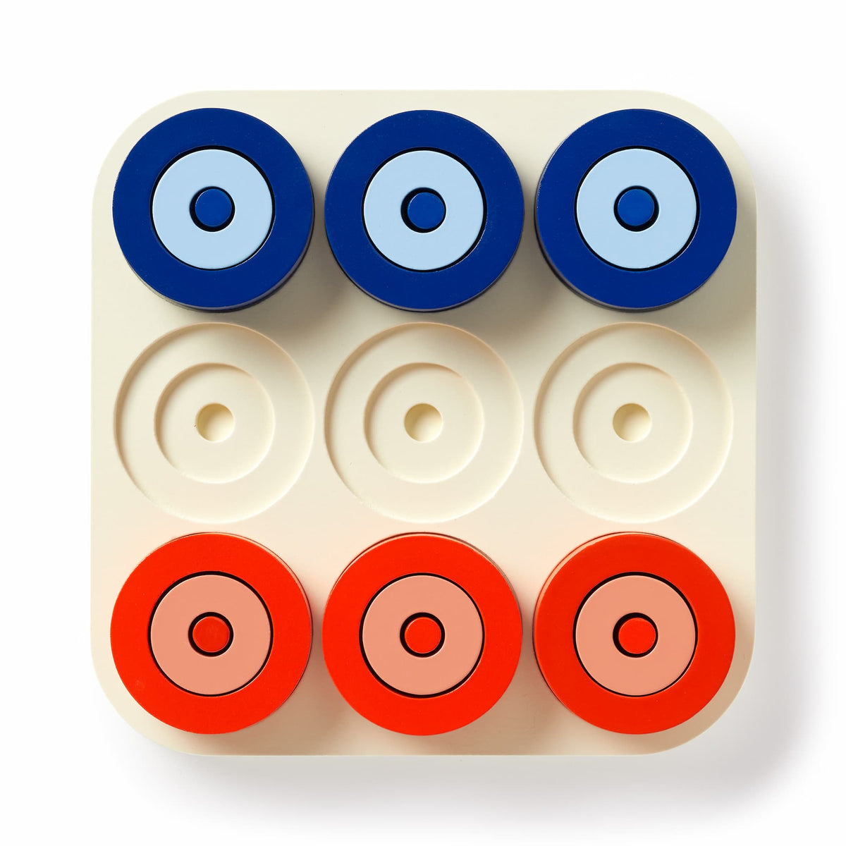 The Brass Monkey Tic Tac Pro Game Set includes a square board with nine circular slots and red and blue painted wood pieces, arranged in two rows. Bottom middle, left center, and right center slots are empty for strategic play.