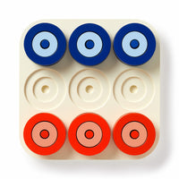 The Brass Monkey Tic Tac Pro Game Set includes a square board with nine circular slots and red and blue painted wood pieces, arranged in two rows. Bottom middle, left center, and right center slots are empty for strategic play.