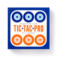 The Brass Monkey Tic Tac Pro Game Set comes in a square box with blue and orange concentric circles on white, featuring painted wood pieces for an advanced version of tic-tac-toe. The subtitle reads: “Advanced tic-tac-toe is a thing. Well, it is now anyway.”.