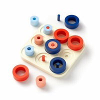 The Brass Monkey Tic Tac Pro Game Set is a colorful wooden sorting toy featuring red, blue, and light pink rings and pegs on a cream base—like an advanced tic-tac-toe with stackable and scattered pieces.