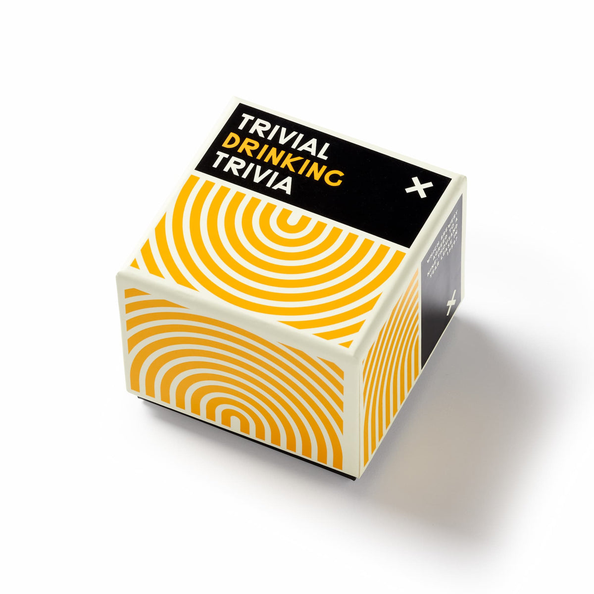 A cube-shaped Trivial Drinking Trivia game box by Brass Monkey, featuring bold yellow spirals on black and white sides, sits on a white surface—offering fun trivia questions and some misleading categories inside.