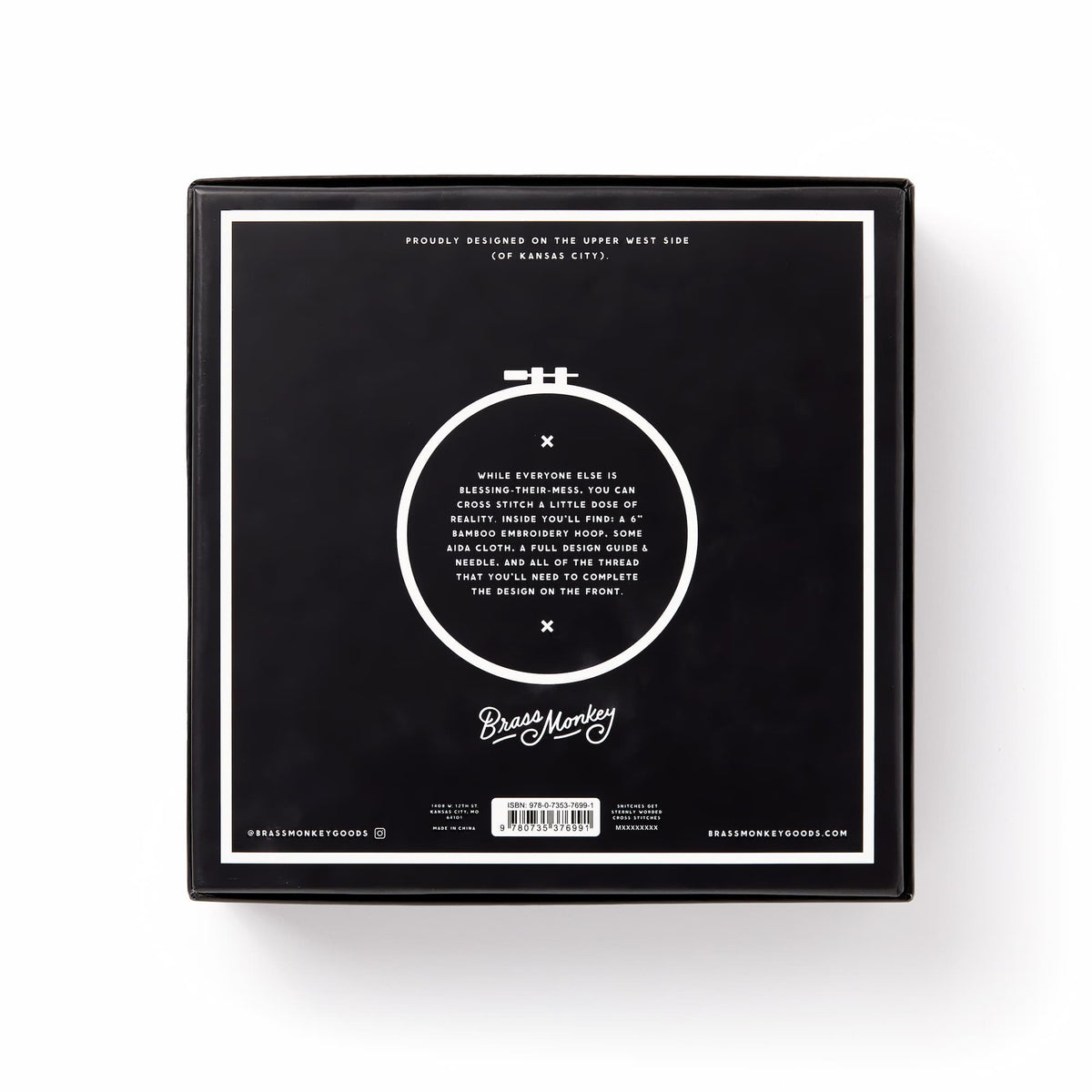 A black square box displays a white circular embroidery hoop with You Light Up A Room Cross Stitch Kit in white text at the center, and Brass Monkey branding at the bottom, set against a plain white background.