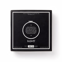 A black square box displays a white circular embroidery hoop with You Light Up A Room Cross Stitch Kit in white text at the center, and Brass Monkey branding at the bottom, set against a plain white background.
