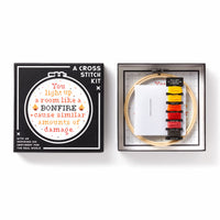 The Brass Monkey You Light Up A Room Cross Stitch Kit features a box lid with stitched text, and includes floss, embroidery hoop, needle, fabric, and a detailed design guide.