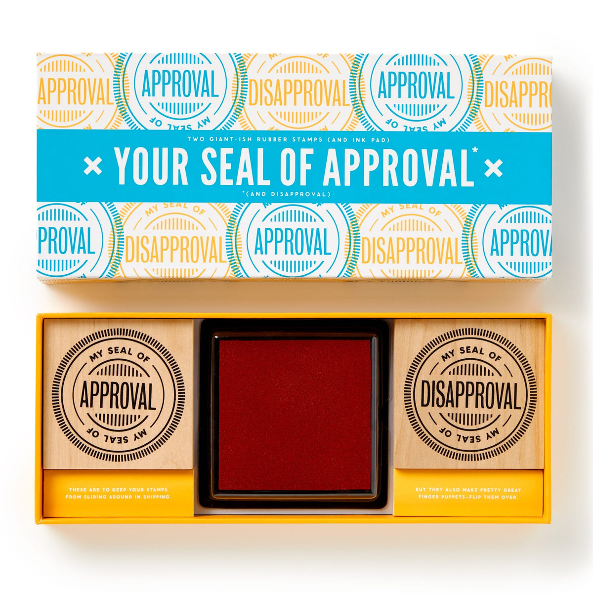 The Brass Monkey Your Seal Of Approval Stamp Set includes two oversized red stamps labeled APPROVAL and DISAPPROVAL, plus a large inkpad. The box features colorful circular designs inspired by stamped impressions.