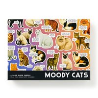 The Brass Monkey Moody Cats 1000 Piece Puzzle features humorous cat illustrations with speech bubbles expressing various moods, set against a vibrant purple, orange, and pink gradient background.