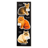 The Brass Monkey Moody Cats Magnetic Bookmark Set features three illustrated cat bookmarks on black, each with witty speech bubbles: “I heard the next chapter is incredible,” “We’ll save your spot,” and “Shhh, I’m here to remind you.”.
