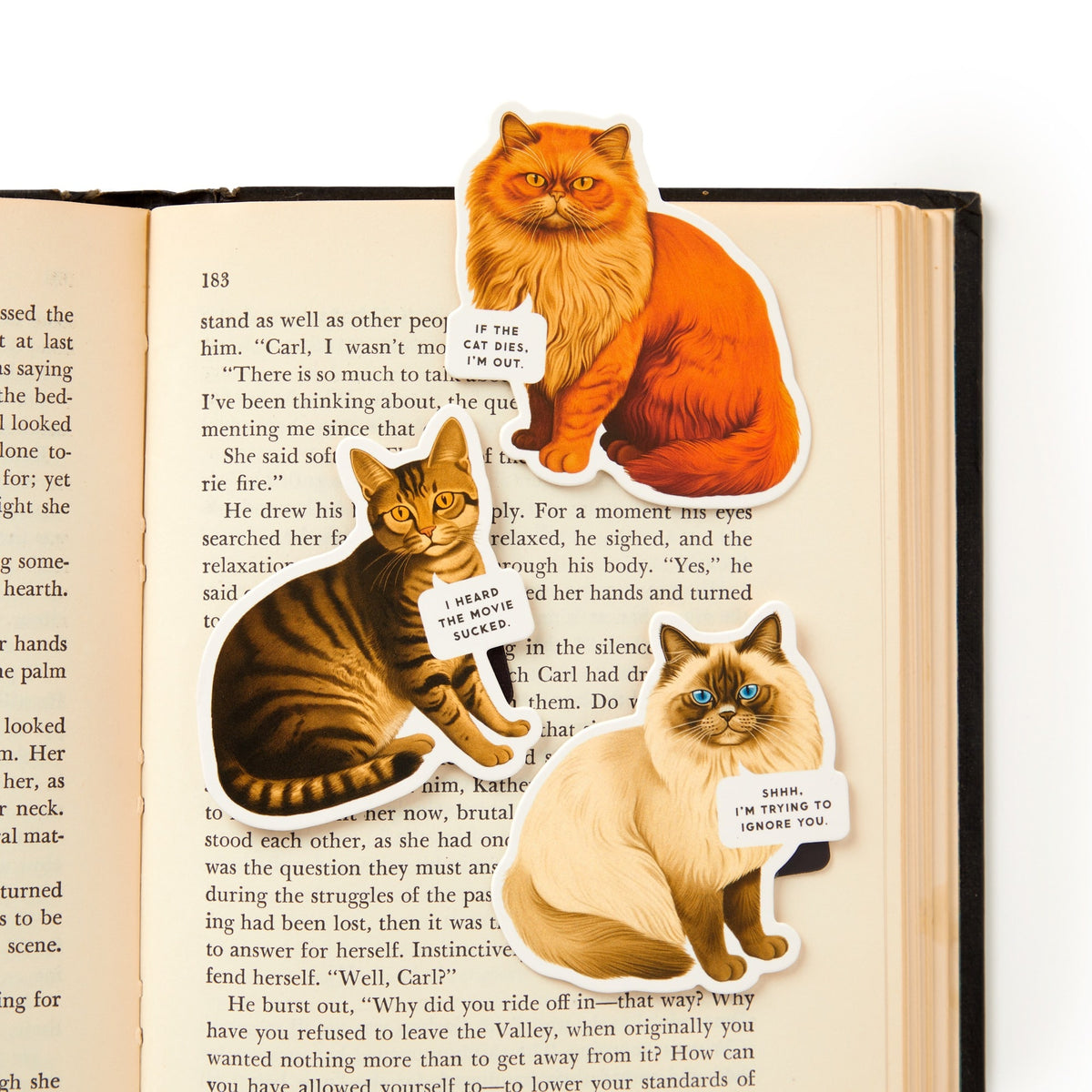 The Moody Cats Magnetic Bookmark Set by Brass Monkey features three illustrated cat bookmarks, each with a funny saying: "I fit, I sit," "I have mixed feelings about you," and "Shhh... I'm trying to ignore you.
