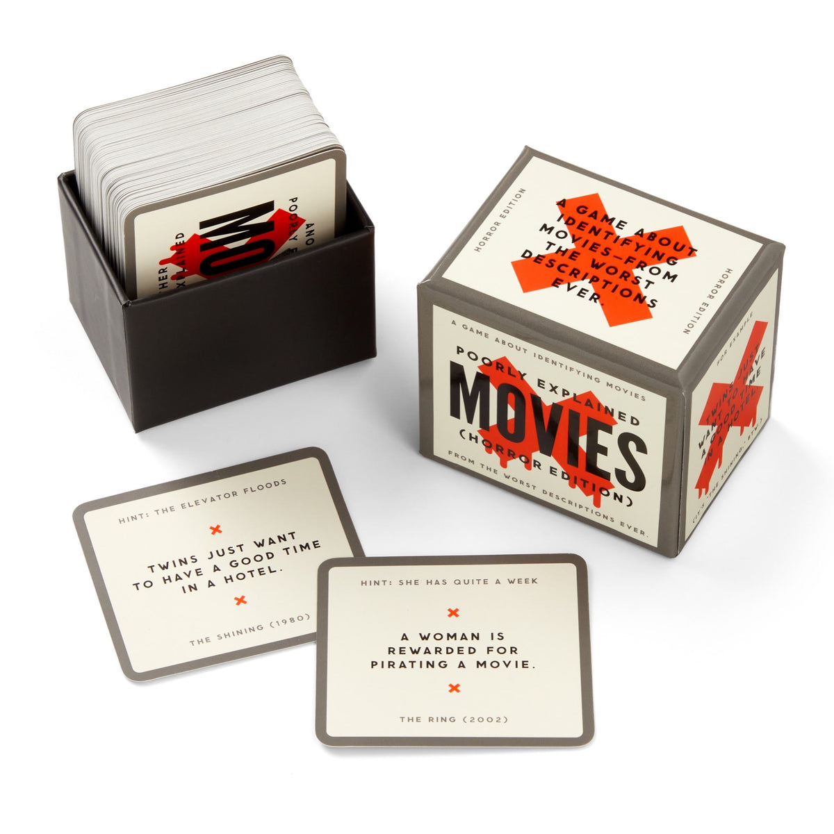 The Brass Monkey Mini Poorly Explained Movies - Horror Edition card game is shown with a stack of cards in a black box and a cube-shaped game box. Two cards reference "The Shining" and "The Ring.