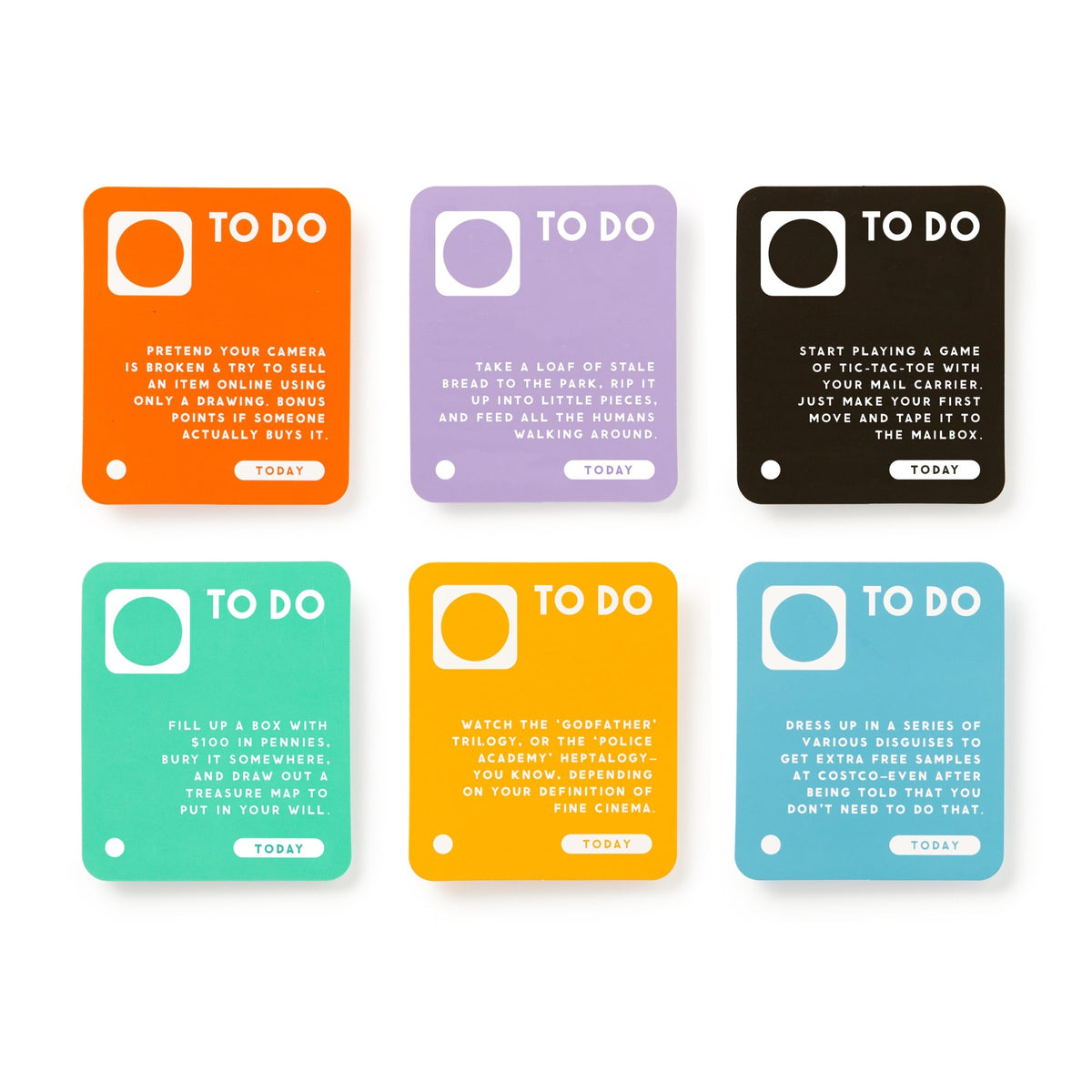 The Brass Monkey Random Things To Do Box includes six colorful square cards with playful tasks like fixing a camera, taking a leap of state, playing a game with tape, filling a box with coins, watching The Godfather, and dressing up in disguises.