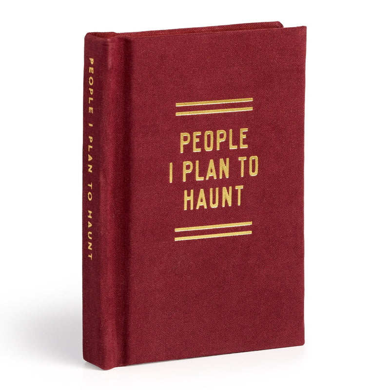 A closed, red hardcover diary from Brass Monkey stands upright, featuring gold lettering on the cover and spine that reads "People I Plan To Haunt Tiny Diary.