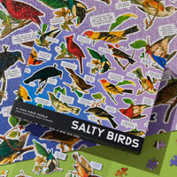 A Brass Monkey Salty Birds 1000 Piece Puzzle box sits atop a half-finished jigsaw, both featuring colorful illustrated birds and witty, salty captions.
